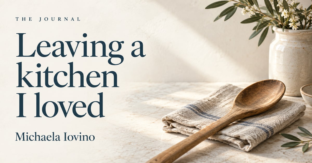 “Leaving a kitchen I loved” by Michaela Iovino, beside a wooden spoon resting on linen.